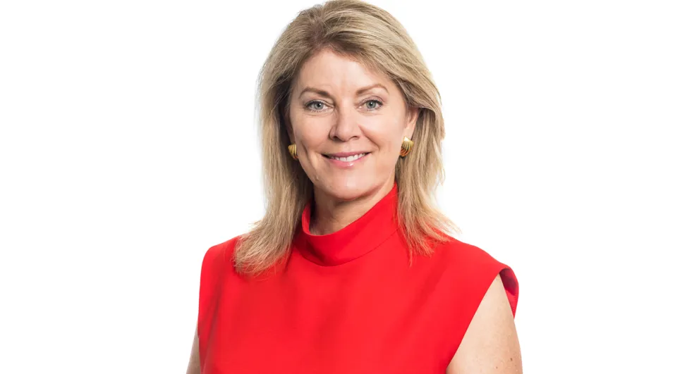 Tracey Hayes wearing a blue top and black blazer on a white background