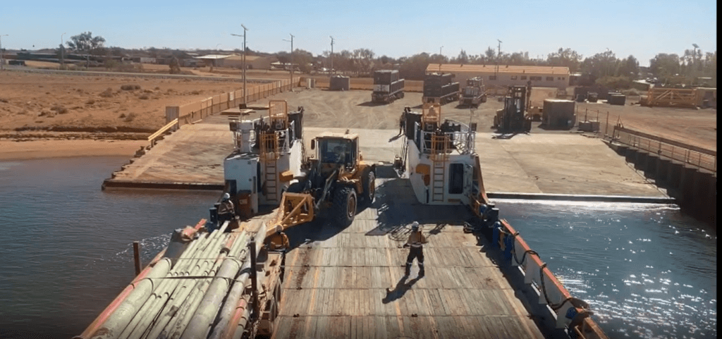 View from the top of a boat docked to the Onslow Marine Support Base with front loader moving assets onto the boat and a worker looking on