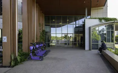 JCU Student Accommodation Main Entrance With Timber Laminate Pillars Glass Fascia Concrete Flooring And Purple Scooters