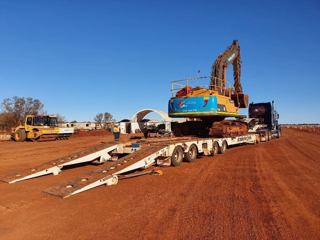 crane on a semi trailer surround by red dirt