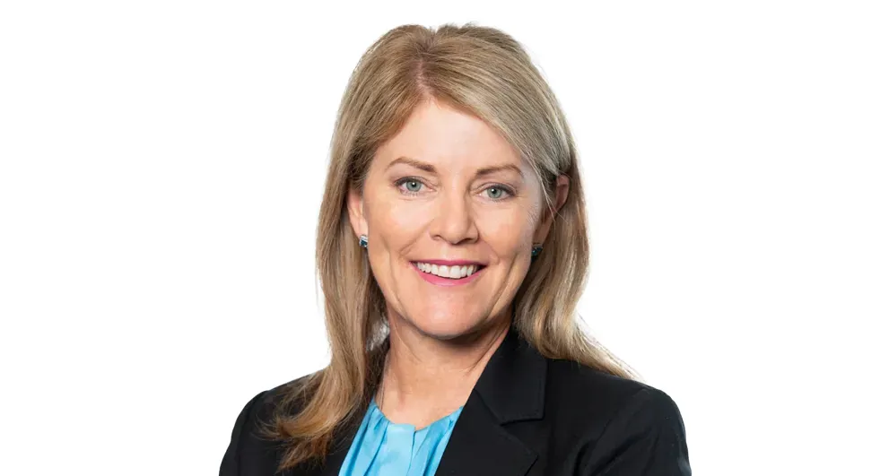 Tracey Hayes wearing a blue top and black blazer on a white background