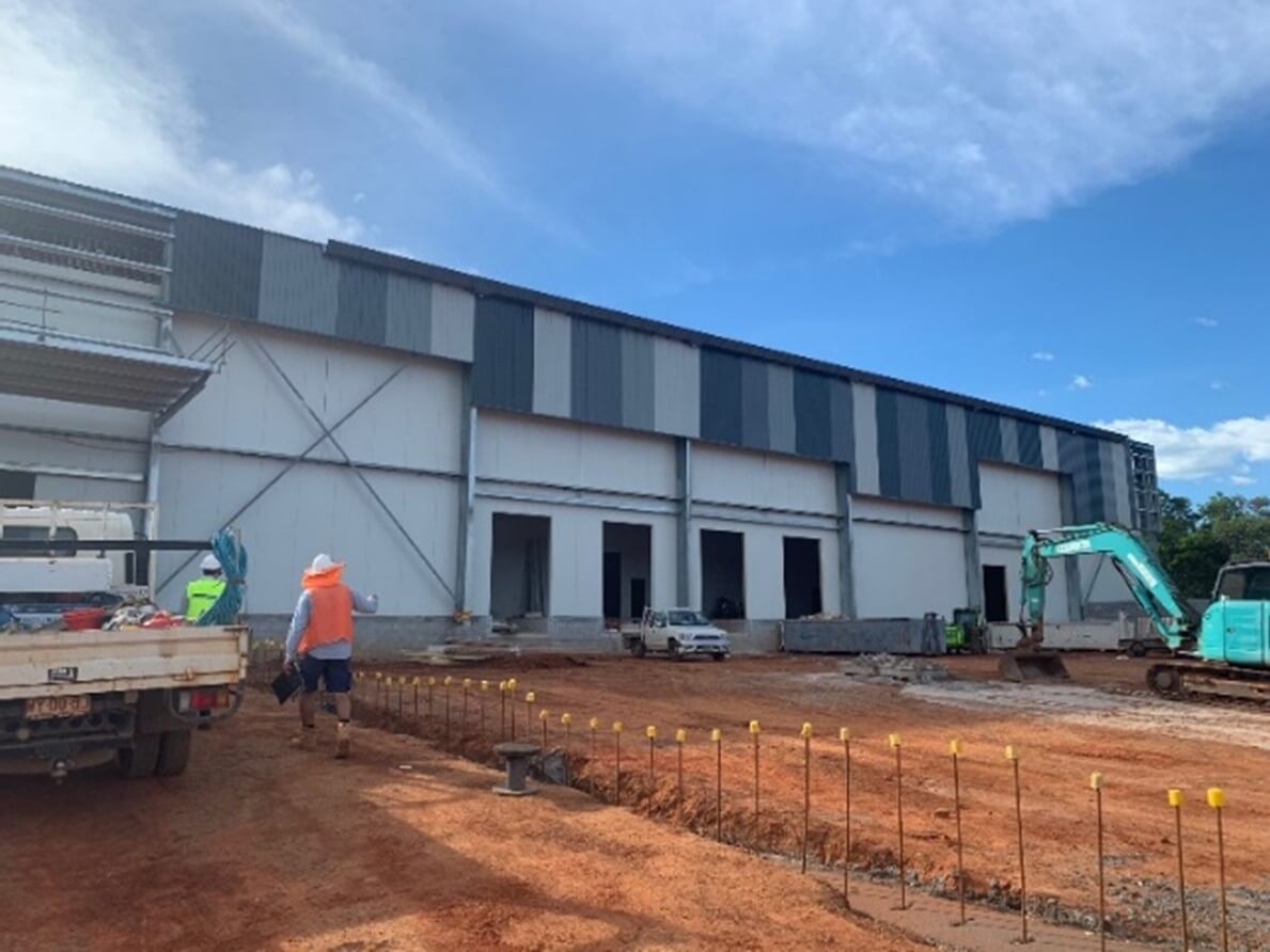 Cold Storage Facility side view of construction with worker, crane and red dirt